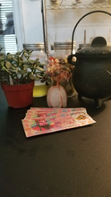 Load image into Gallery viewer, This is an image of a table with ancestor money (aka joss paper), a crystal money tree, a cauldren with the Tree of Life, my Money essential oil blend, and my Money herb blend.